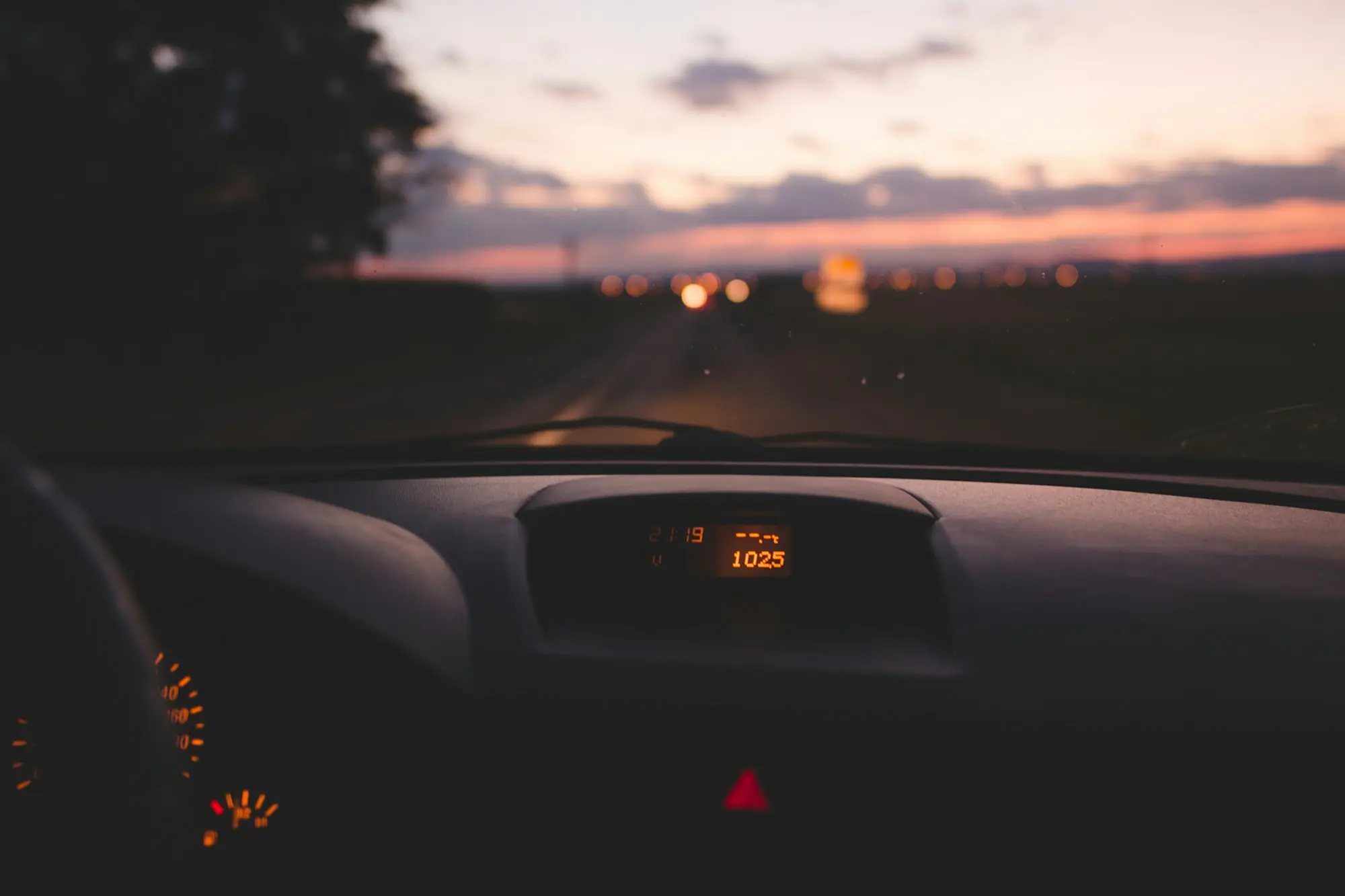 Carretera al atardecer vista desde el interior de un coche, con el tablero en penumbra